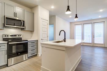 a white kitchen with a large island and stainless steel appliances